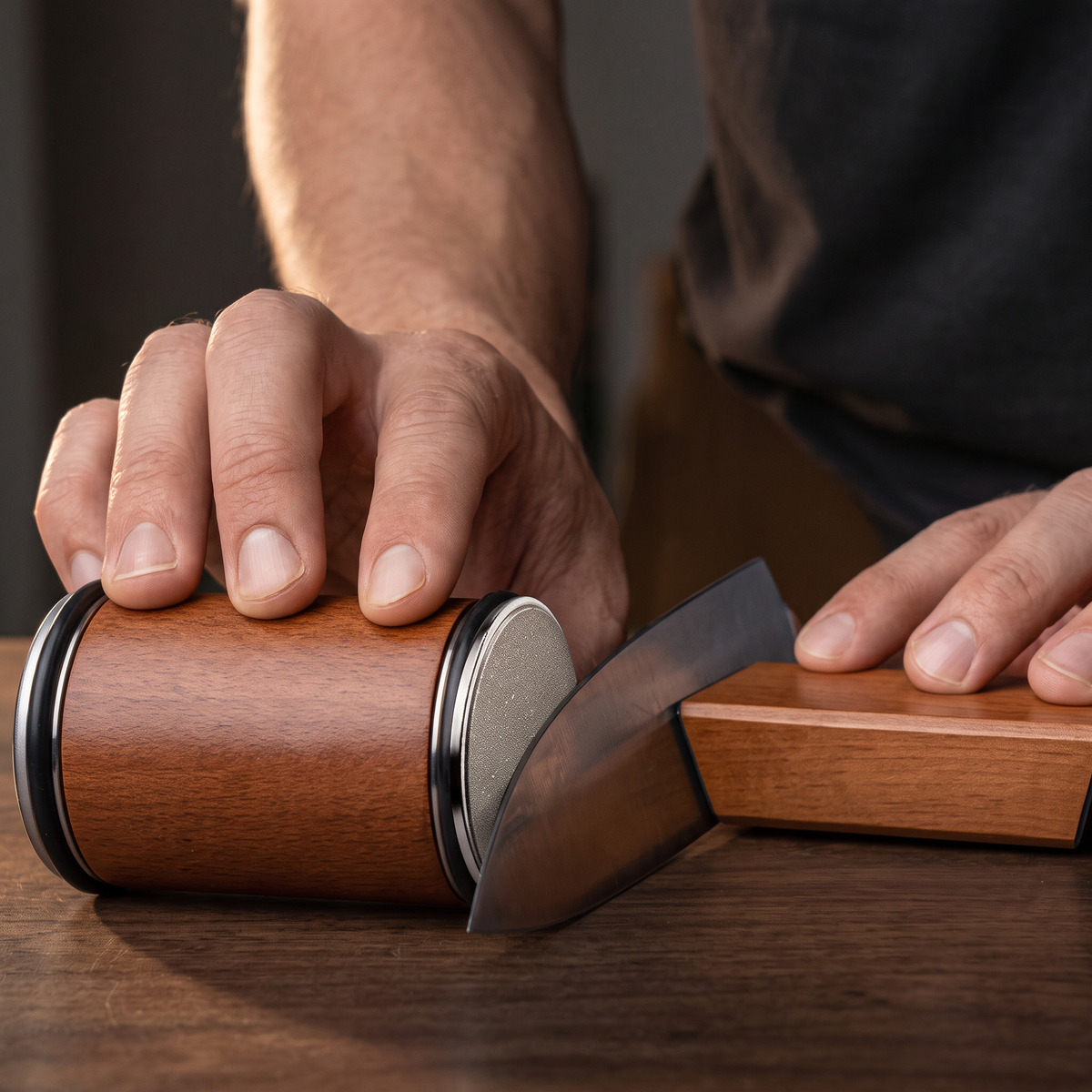 Hand rollt die Walze, die Stahlscheibe läuft an der Klinge, die andere Hand hält den Block